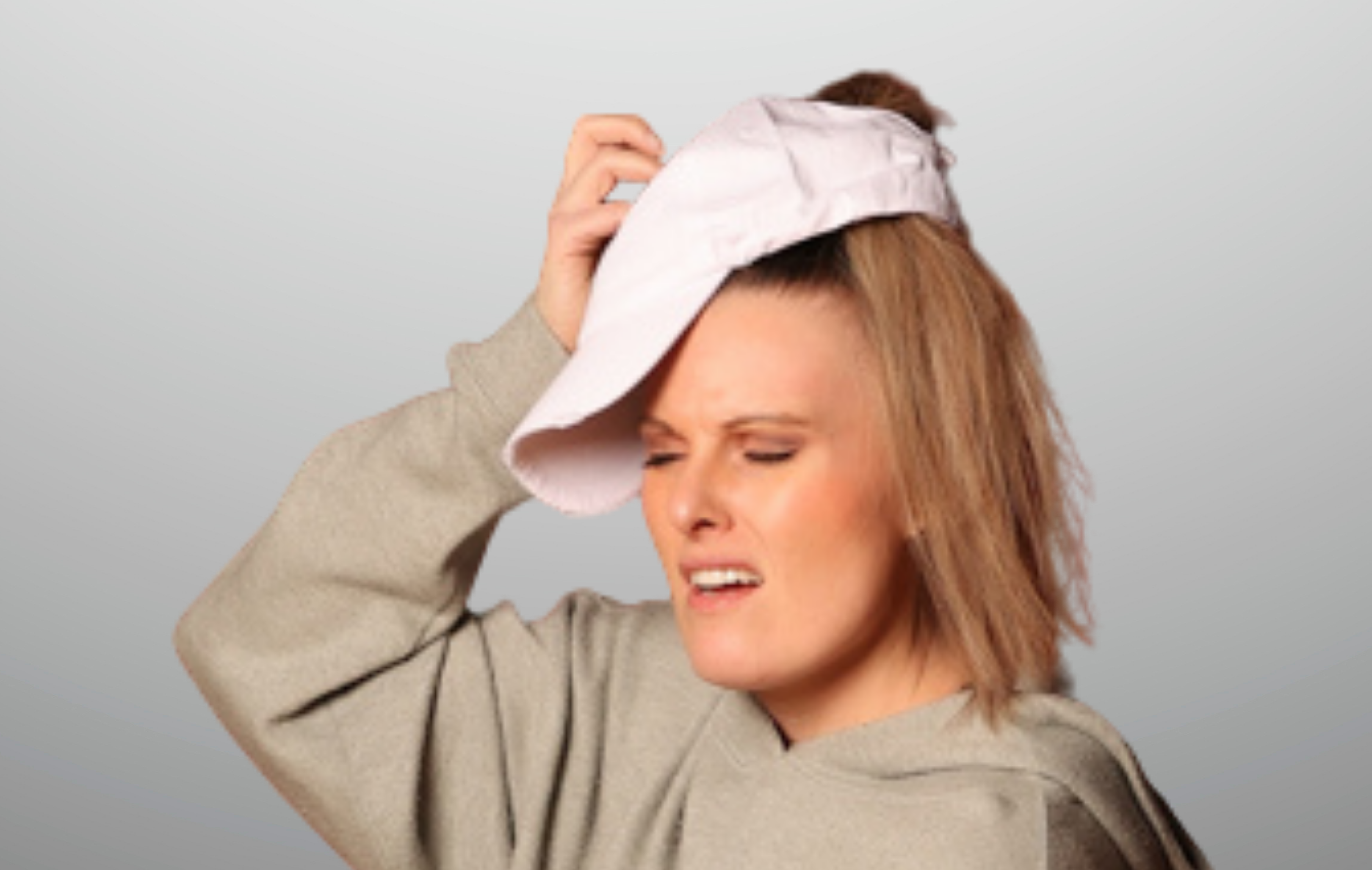 Woman wearing a ponytail hat with a poor fit and a frustrated expression.