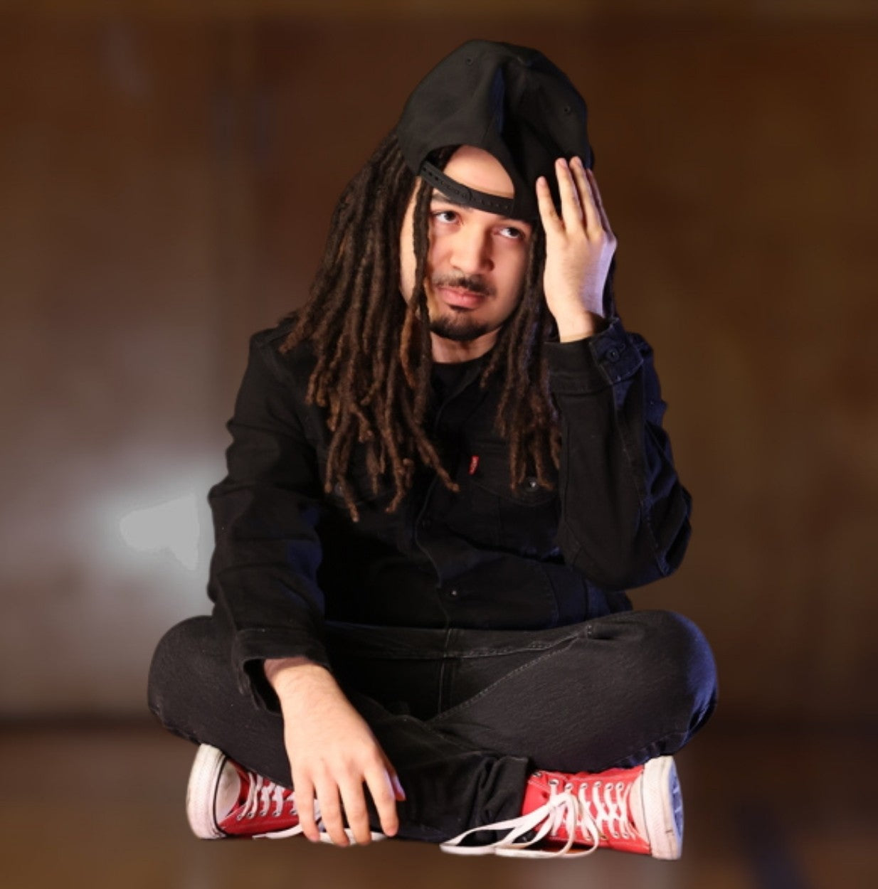 Model with locs wearing a regular baseball cap that sits too shallow and awkwardly on the head.