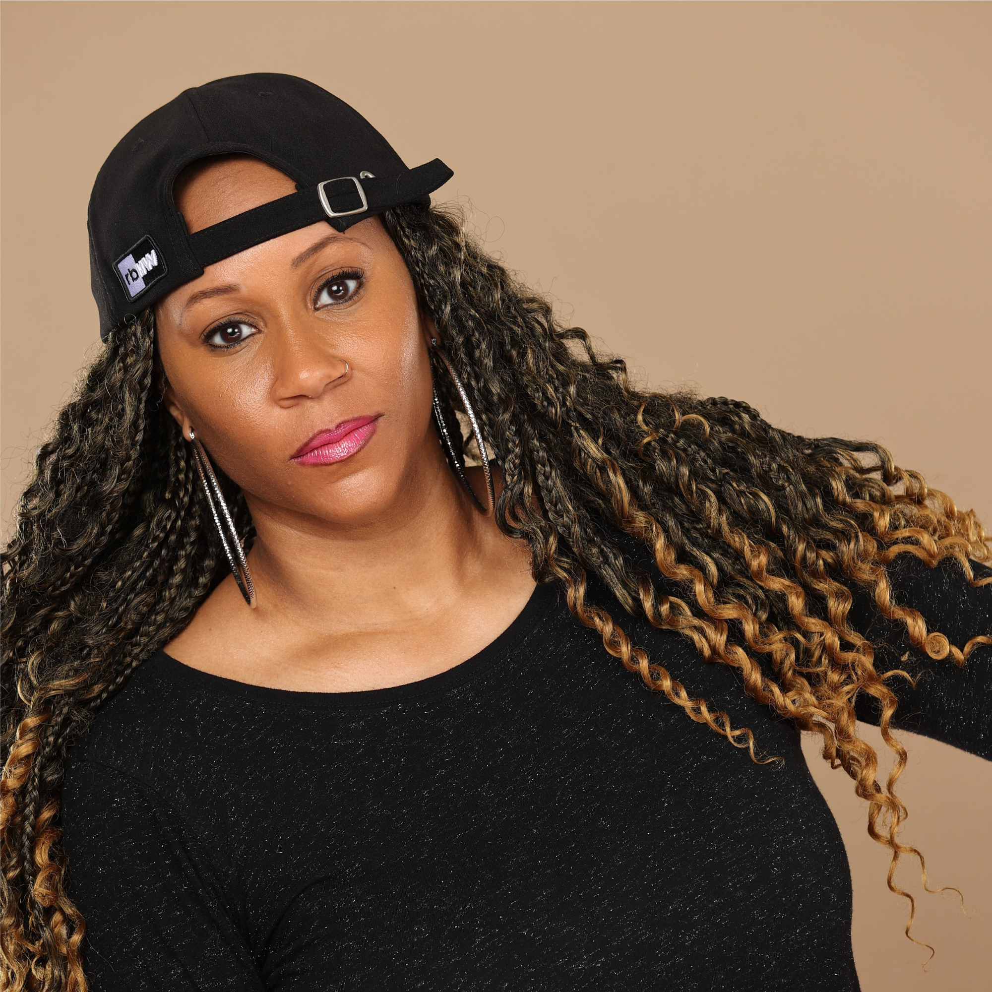 Model wearing backward the black Rosebloom HLO closed crown hat, showing room for locs, textured hair, and protective styles.
