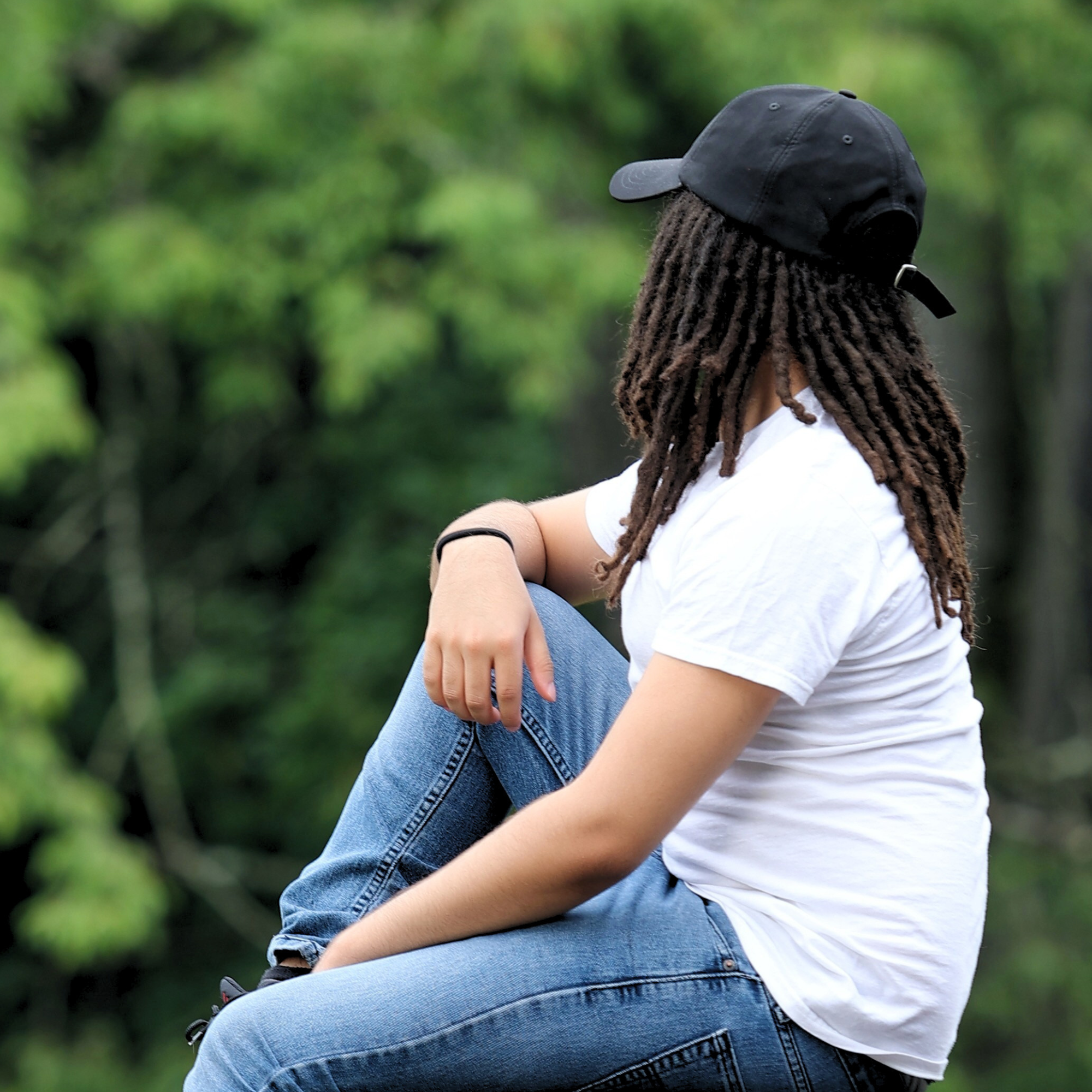 Model shown from behind wearing the black Rosebloom HLO closed crown hat, showing room for locs, textured hair, and protective styles.