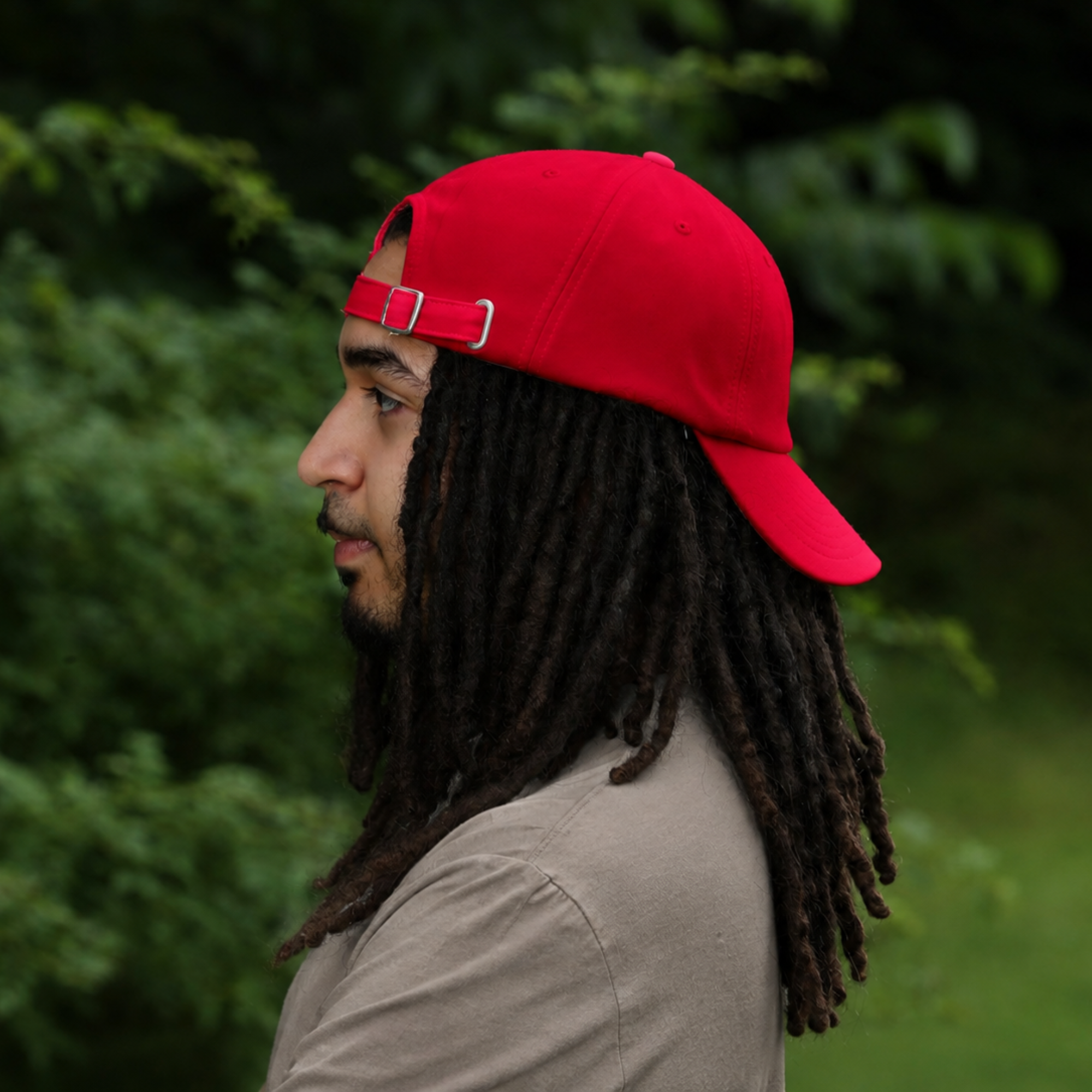 Model wearing backward the red Rosebloom HLO closed crown hat, showing room for locs, textured hair, and protective styles.