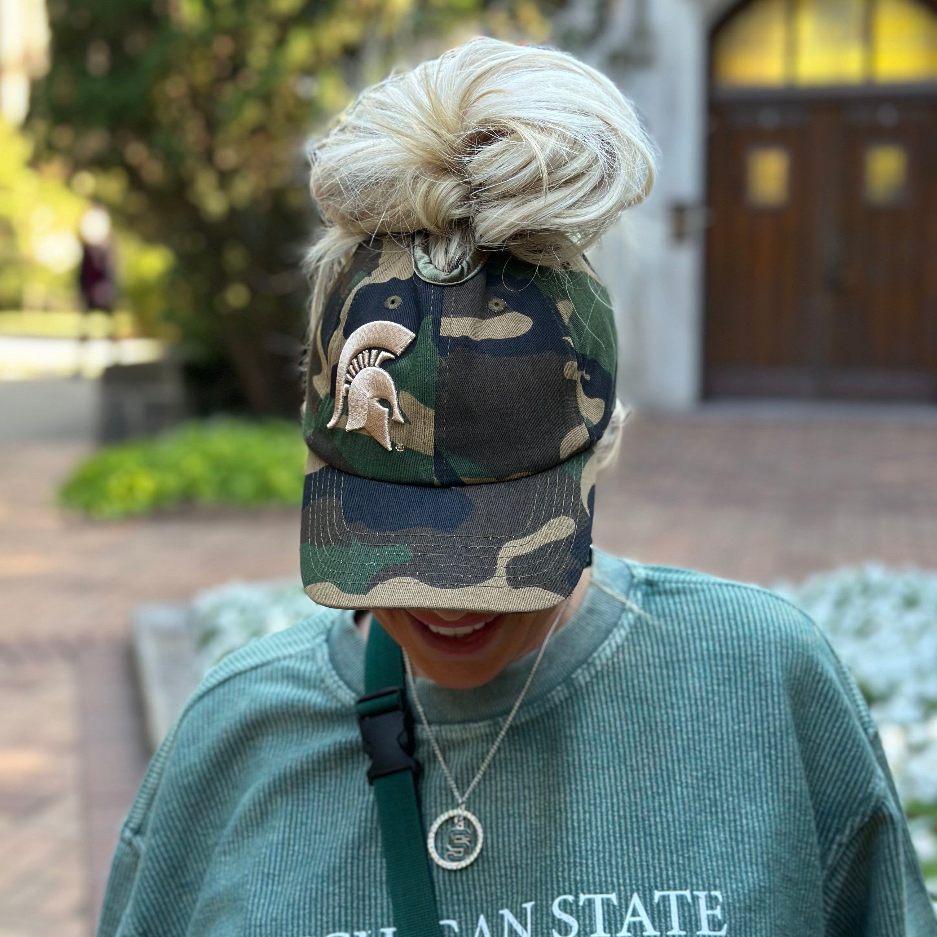 Front lifestyle view of a model wearing the camo Rosebloom Michigan State PNT high ponytail hat with an embroidered Spartan logo and hair pulled through the crown opening.