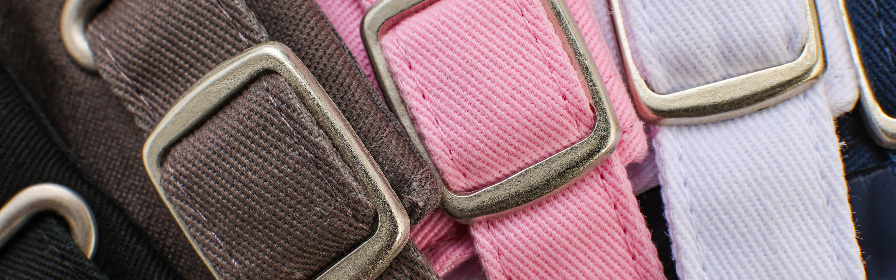 Close-up product detail of Rosebloom NZR and Compassion Cap strap closures in multiple colors, highlighting the adjustable fabric straps and metal hardware.