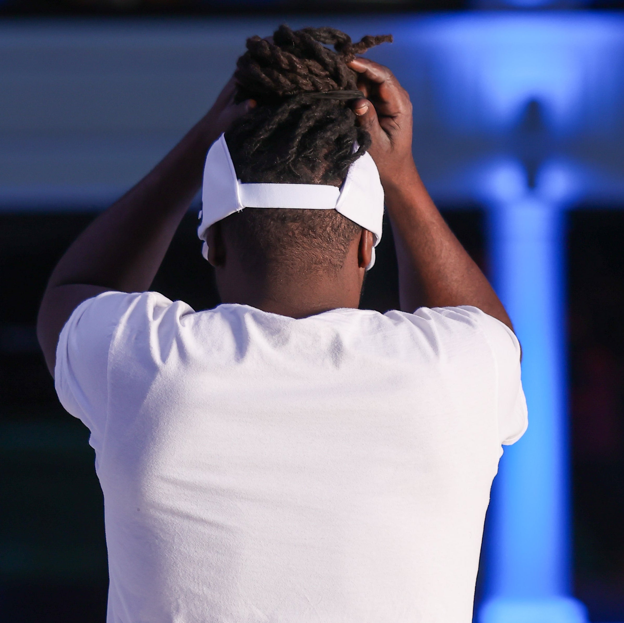 Back view of a model wearing a white Rosebloom GZO STRETCH with locs pulled through the crown-height opening, showing the back fit and hair-accommodating design.