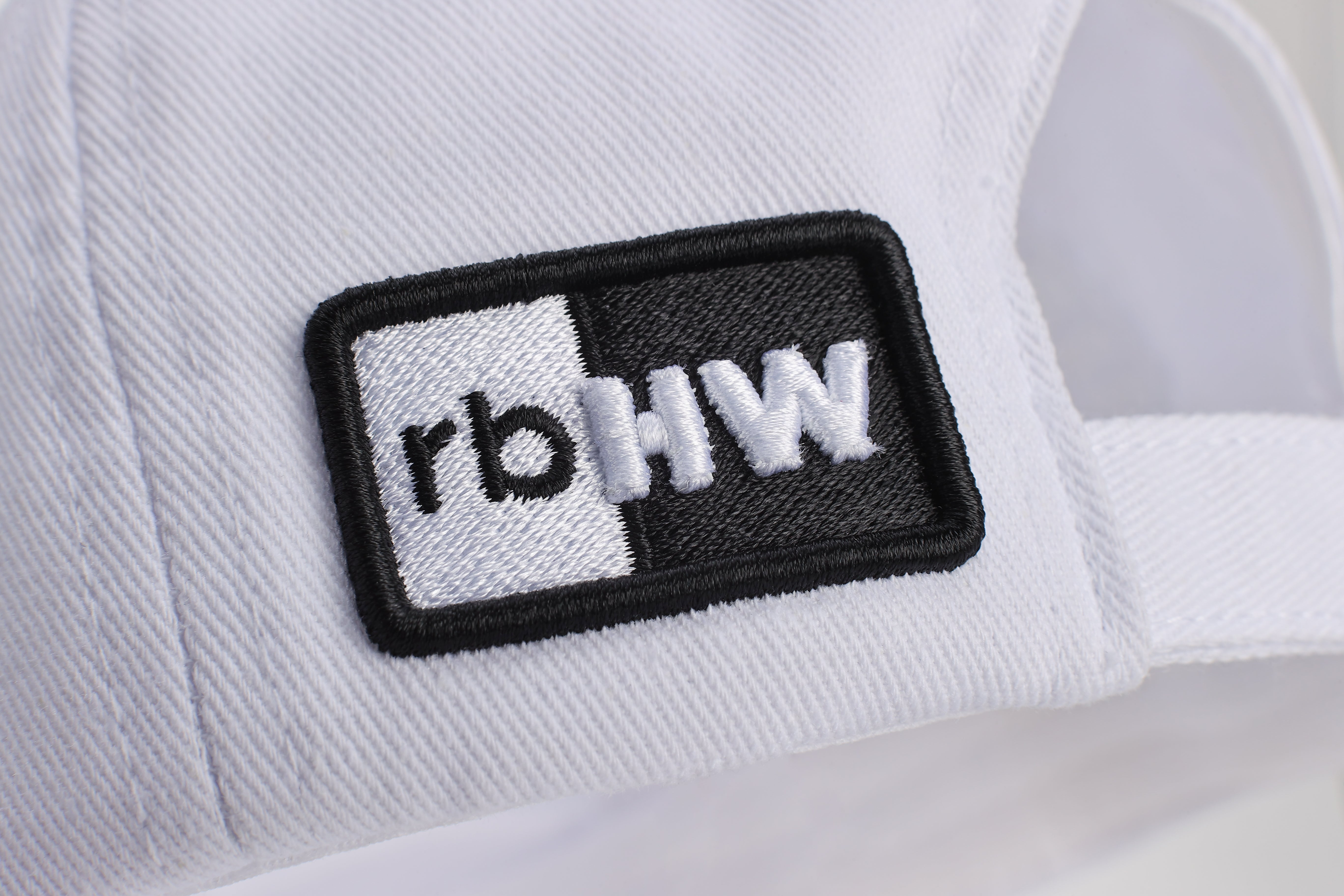 Close-up detail of the stitched Rosebloom Headwear logo patch on the back of a white NZR hat.