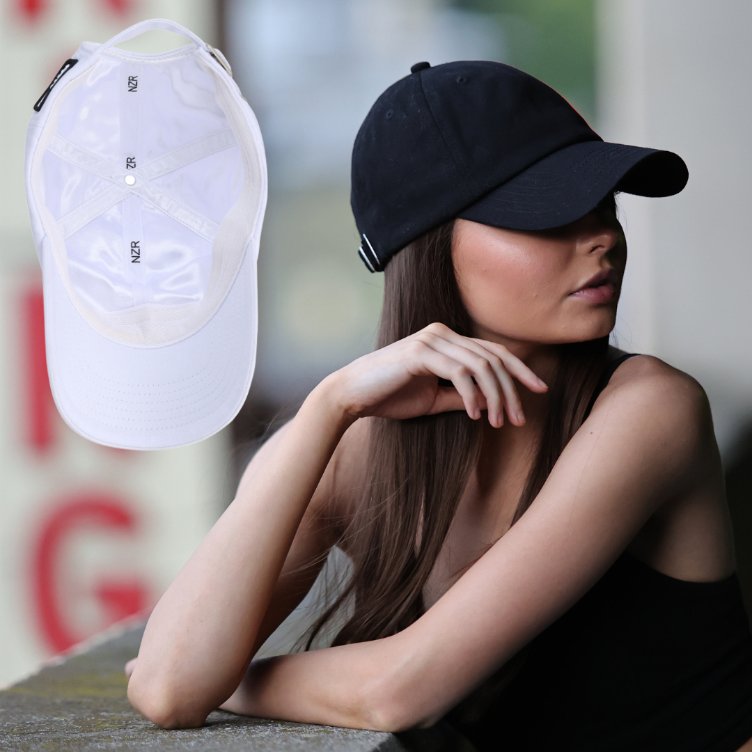 NZR WEBSITE a young woman is wearing a black satin lined baseball hat that is perfectly fit for her head and hair. she has long straight brown hair and a slight, feminine build. there is a photo of the interior of the hat showing the satin lining.