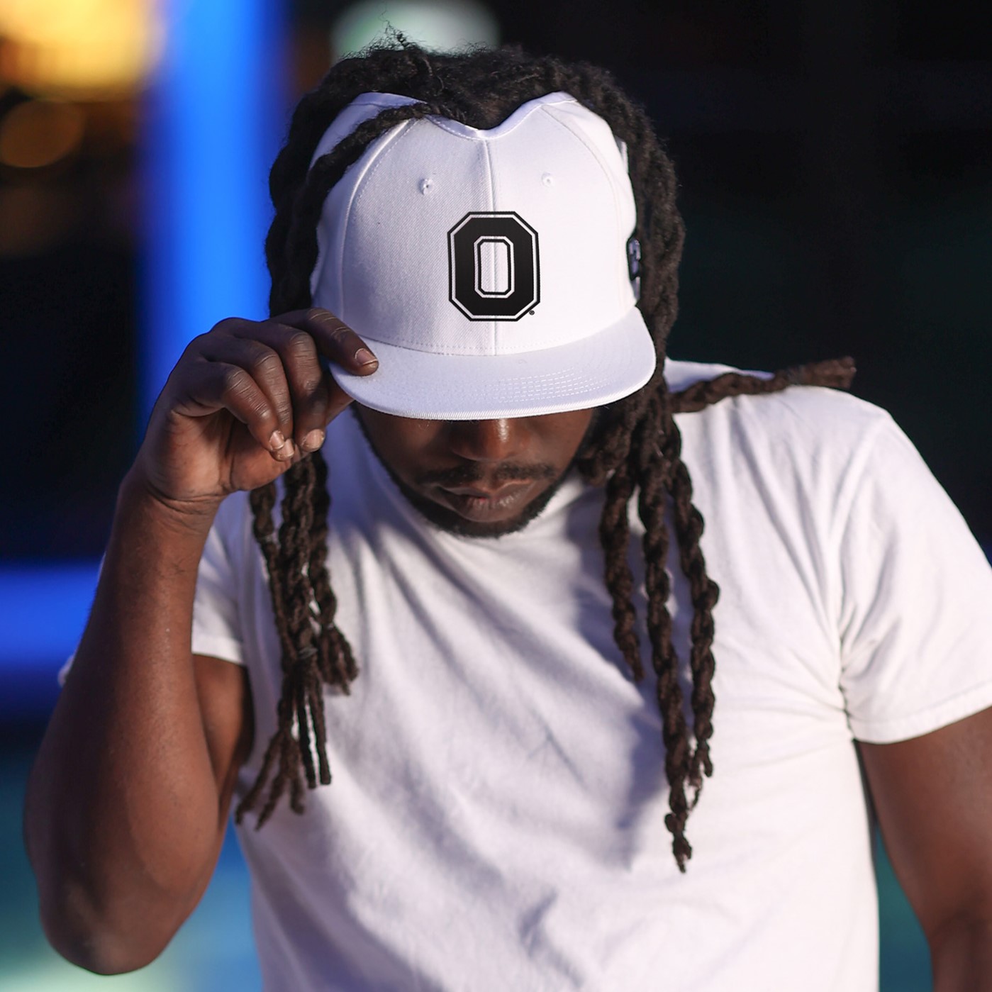 Ohio State hat for locs A man with locs wears a white flat bill hat with a crown height opening and a black Block O Ohio State logo